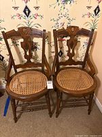 Front view of both wood dining armchairs with cane seats