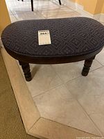 Overall view of footstool showing upholstery and legs