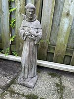 Front view of concrete monk statue holding bird