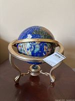 Full view of gemstone globe on metal stand with compass visible