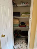 Closet shelves showing folded sheet sets, blankets and comforter