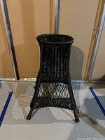 Front view of black wicker plant stand
