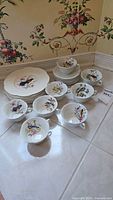 Plates, cups and saucers grouped; shows bird motif and quantity