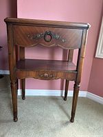 Front view showing drawer, shelf, legs and floral detail