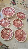 Stacks of red and white Spode plates, showing both large and small sizes