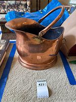 Front view of copper coal scuttle with swing handle and base