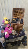 Basket on table, yarn skeins inside and surrounding, quilt top under items