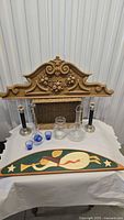 All items grouped on table: angel plaque, frieze, candlesticks, glassware, basket