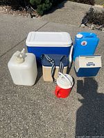 All items grouped: large blue cooler, two water containers, two small coolers, red mug