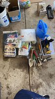 All items laid out including packaged frost blanket, netting, watering can, hand tools