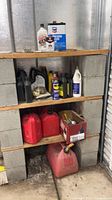 Shelved collection showing oil containers, gas cans, rope and box of tools