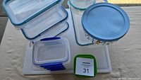 Stacked Snapware plastic containers, round Christmas glass container, cutting board, small green-lidded container visible
