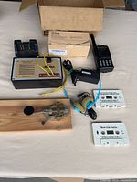 Group shot of all items: radio, oscillator, key, charger, adapter, headphones, tapes