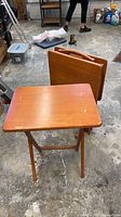 Three wooden folding TV trays on stand in garage setting
