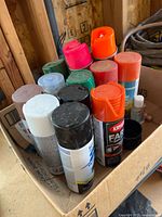 Top view of box showing mix of aerosol cans with varied cap colours