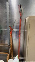 Both pole pruners leaning against wall