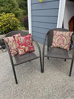 Two brown resin wicker chairs with pillows in situ