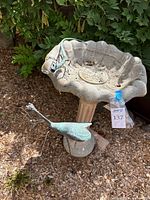 Concrete birdbath with praying mantis sculpture on rim and lizard sculpture nearby