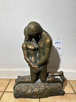 Front view of bronze-tone sculpture showing full figures and base