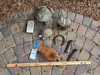 Group shot of all cement figurines, terra-cotta duck, iron hardware and ruler for scale