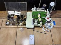 Wide view of serger, organizer box, thimbles and thread