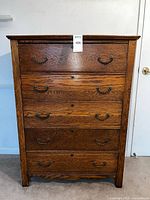 Front view of oak five-drawer dresser showing hardware and overall condition