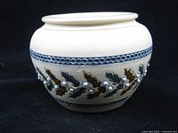 Side view of stoneware pot showing relief decoration and blue banding