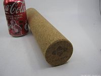 Cork massage roller beside soda can for scale, showing length