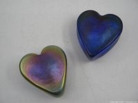 Two iridescent glass heart paperweights, blue and multicolor