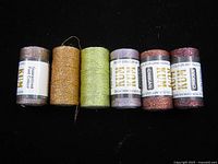 Front view of six Kum Chikan thread spools showing labels and colours