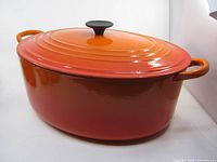 Full view of Le Creuset oval Dutch oven with lid on showing flame finish and handles