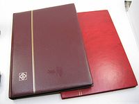 Two closed stamp albums, maroon and red covers