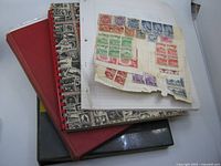 Three albums stacked with loose stamp page on top