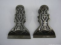 Front view of both ornate metal clips showing scrollwork design