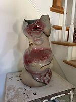 Front view of ceramic abstract female torso vase placed on a small table