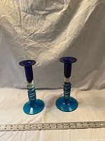Two blue and aqua glass candlestick holders with ruler for scale