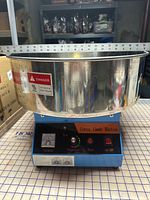 Front view showing entire cotton candy machine with bowl, controls, voltmeter, temperature dial, fuse button, on/off switch
