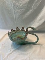 Left side view of blown glass swan-form dish showing ruffled rim and curved neck handle