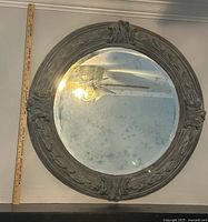 Front view of round mirror beside yardstick for scale