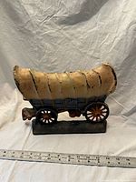 Profile view of metal covered wagon sculpture with ruler for scale