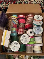 Open box showing assorted ribbon spools and cord