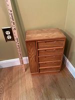 Front view of closed oak jewelry box next to ruler