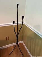 Full view wrought iron floor-standing candle holder showing three candle cups and tripod base