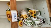 Shelf with sunflower vase, small sunflower creamer, teapot, pitcher, gravy boats and Christmas tree mug