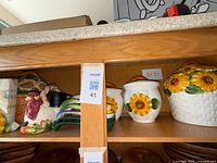 Shelf view showing three white sunflower canisters, large white basket-weave sunflower canister, stack of lids