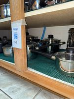 Shelf showing multiple stainless steel saucepans and stock pots with lids
