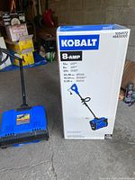 Retail box showing Kobalt 8-amp electric snow shovel specifications with separate shovel head on floor