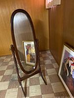 Full view of oval wooden floor mirror with frame and stand