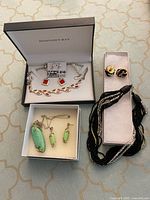 Three boxed jewellery sets: red enamel bracelet and earrings in Hudson’s Bay box, green stone necklace and earrings, black seed-bead necklace with matching earrings