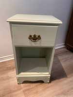 Front view of green wooden side table with drawer and lower shelf